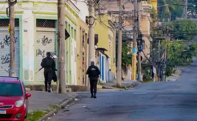 Two armed police officers walk through an almost deserted street in Rio De Janeiro. At least eleven people have died in a police operation against the heads of the Comando Vermelho (Red Command) Criminal organization. (Best possible quality)