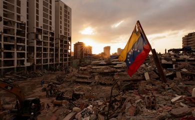 Uma bandeira venezuelana tremula enquanto pessoas procuram os corpos de seus entes queridos sob os escombros, após os terremotos que abalaram a Venezuela em 24 de junho, em Caraballeda, La Guaira, Venezuela 29 de julho de 2026 REUTERS/Gaby Oraa