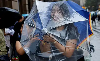 Uma pessoa segura um guarda-chuva para se proteger dos ventos fortes antes da chegada do tufão Dolphin em Xangai, na China, em 9 de agosto de 2026. REUTERS/Go Nakamura