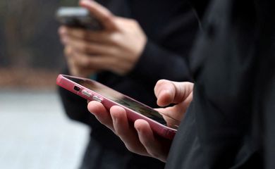 Adolescentes olham para as telas de seus celulares em Paris 20 de fevereiro de 2026 REUTERS/Manuel Ausloos
