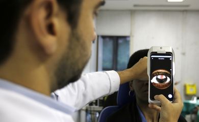 O Dr. Flávio Medina realiza exame de fundo de olho com um retinógrafo portátil,