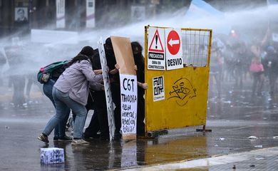 Demonstrators take cover with makeshift shields from water cannons during a protest in support of the Argentine university community, demanding increased funding and what organisers call fair wages for the sector, and against President Javier Milei's administration, in Buenos Aires, Argentina, October 15, 2026. REUTERS/Pedro Lazaro Fernandez